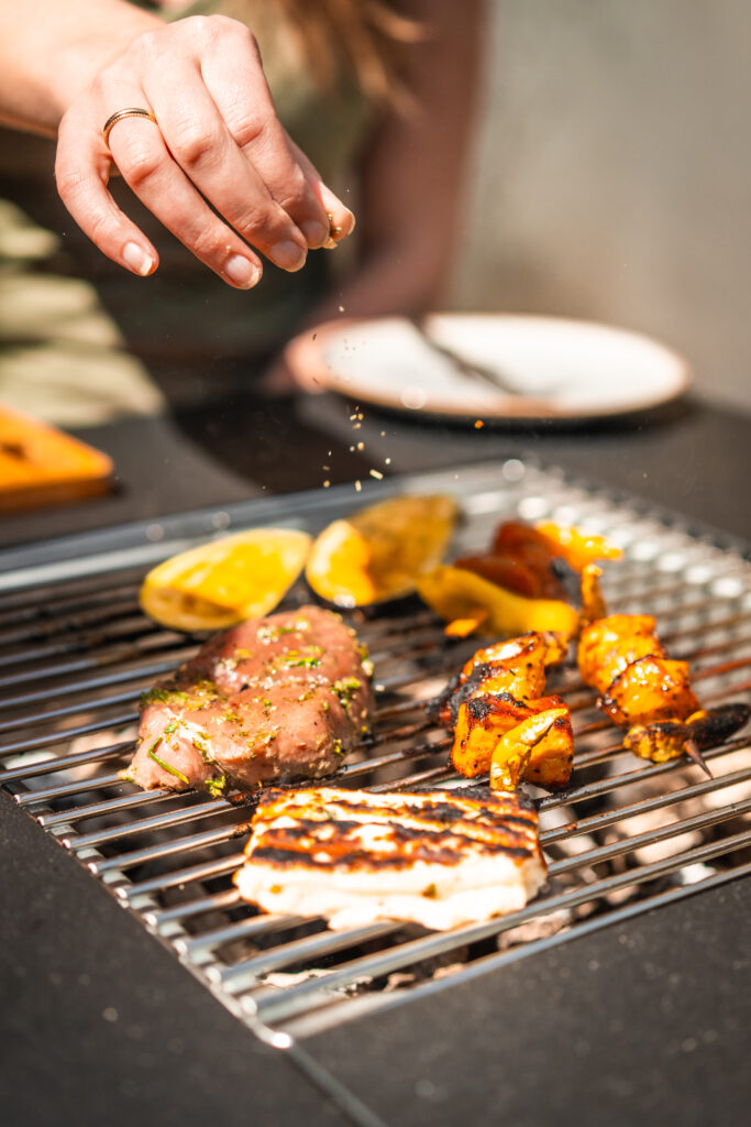 Grillfleisch würzen auf Kohle Feuertisch von Meateor